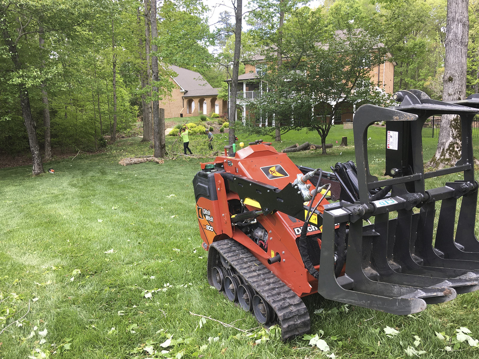 Tree Removal And Storm Cleanup Machine Operating In A Garden Area With Many Trees And Grass In A Large Field